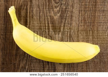 One Whole Fresh Yellow Banana Flatlay On Brown Wood