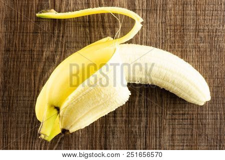One Whole Opened Fresh Yellow Banana Flatlay On Brown Wood