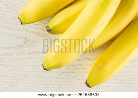 Group Of Five Whole Fresh Yellow Banana Flatlay On Grey Wood