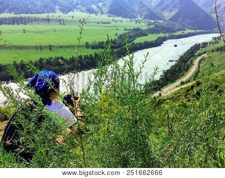 A Man Sits On The Hill And Looks Out Over The River Into The Distance