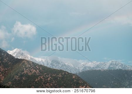 Panorama Of The Rainbow Against The Background Of Snow-capped Mountains In The Clouds