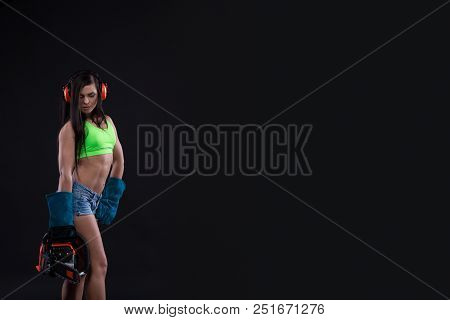 Studio Photography Of A Girl With A Chain Saw On Dark Background. Sexy Builder Woman. Copy Space