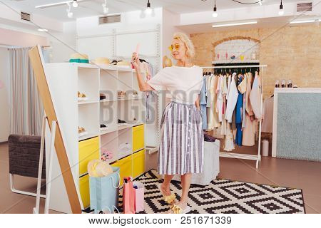 Midi Skirt. Blonde-haired Woman Wearing Midi Skirt And White Shirt Making Photo In Showroom