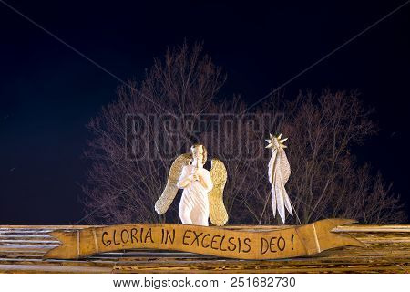 Night Christmas View On A Wooden Sculpture Of An Angle And Comet Star On Wooden Roof. Sign With Read