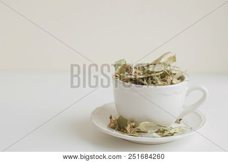 Lime Flower Tea In A White Cup On White Table. Dried Herbal Drink