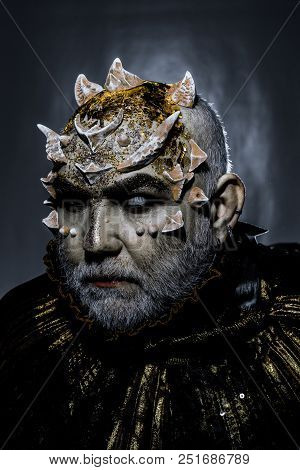 Demon With Golden Collar On Black Background. Man With Thorns Or Warts, Face Covered With Glitters. 