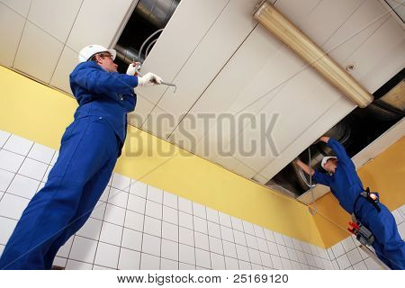 Due operai che lavorano su tubazioni a soffitto