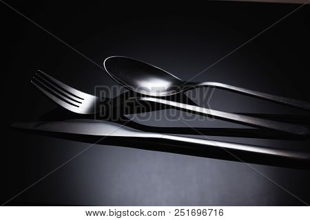 Set Of Stainless Steel Cutlery On A Black Reflective Background, Restaurant Concept