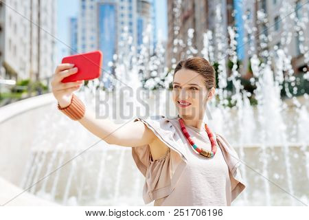 Modern Igen. Delighted Pretty Woman Using Her Smartphone Camera While Taking Selfies