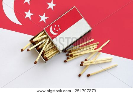 Singapore Flag  Is Shown On An Open Matchbox, From Which Several Matches Fall And Lies On A Large Fl