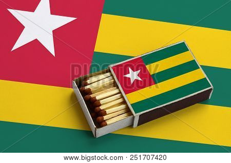 Togo Flag  Is Shown In An Open Matchbox, Which Is Filled With Matches And Lies On A Large Flag.