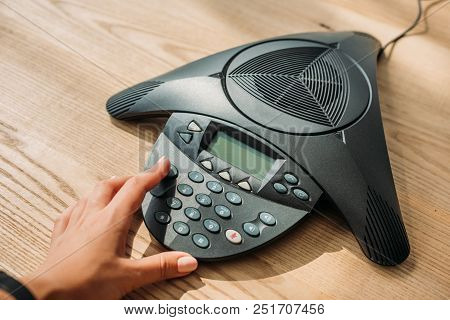 Cropped Shot Of Businesswoman With Pink Nails Pushing Button Of Speakerphone At Workplace