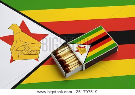 Zimbabwe Flag  Is Shown In An Open Matchbox, Which Is Filled With Matches And Lies On A Large Flag.