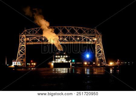 Duluth Minnesota Aerial Lift Bridge With Ore Ship In Canal Leaving Harbor At Night