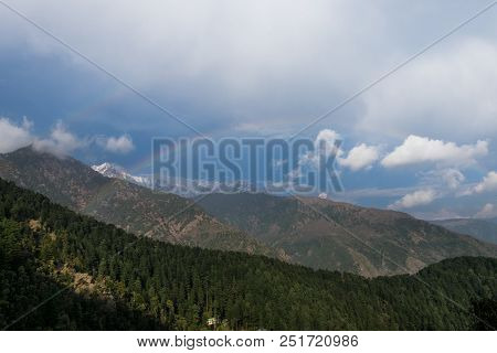 Panorama Of The Rainbow Against The Background Of Snow-capped Mountains In The Clouds