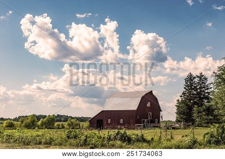 Country Landscape Of Dramatic Cumulus Clouds Over A Red Barn In The Midwestern United States.