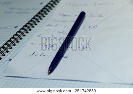 A Exercise Book For Practising Math In Home. Blue Pen With Papers Are Casual Things For Studying On 