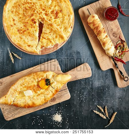Set of Georgian and Adjarian Khachapuri Dishes on Black Rustic Background Top View. Homemade Ajarian Khachapuri, Megrelian and Grilled Khachapuries with Cheese Close Up Collection