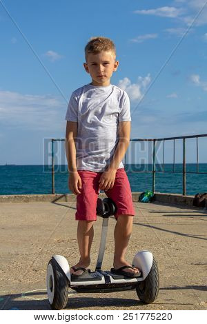 Child On Hover Board. Kids Riding Scooter In Summer Near The Sea. Balance Board For Children. Electr