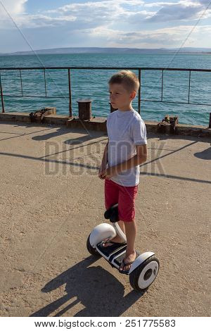 Child On Hover Board. Kids Riding Scooter In Summer Near The Sea. Balance Board For Children. Electr