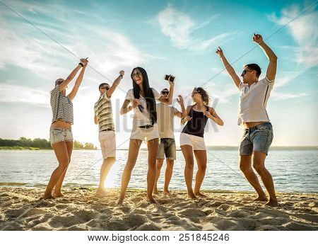 Friends funny dance on the beach under sunset sunlight. Sunny day and friendship.