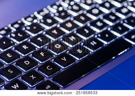Backlit Laptop Keyboard Close-up With Selective Focus In A Blue Ambiant Light
