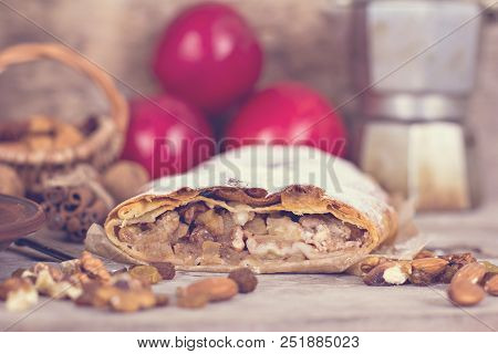 Sliced Homemade Apple Strudel Served With Fresh Apples, Cinnamon Sticks And Sugar Powder Over Old Wo