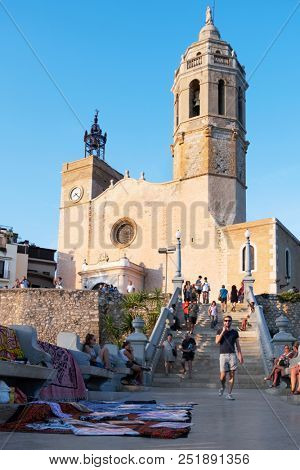 SITGES, SPAIN - JULY 27, 2018: People walking up and down the staircase to the Sant Bartomeu i Santa Tecla Church, in the old town of Sitges, Spain