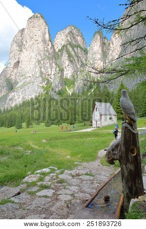 A Wooden Fountain With Carvings Along Vallunga Valley Above Selva With  Saint Silvestro Chapel And M