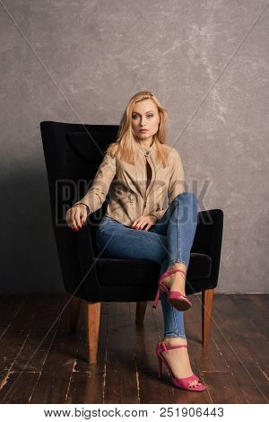 Adalt Lady In Jeans And A Leather Jacket Posing In The Armchair Having A Rest