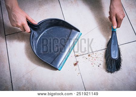 Cleaning Dust On Tile Floor With A Brush And Dustpan Holded By Female Hands, High Angle View