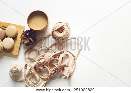 Top View Of A Cookie With Latte And Spruce Cone And A Yarn. Coffee, Four Macarons And Spruce Cone An