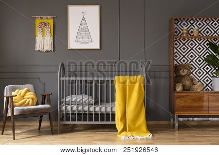 Real Photo Of A Baby Cot With Yellow Cot Standing Between An Armchair And A Cupboard With Teddy Bear