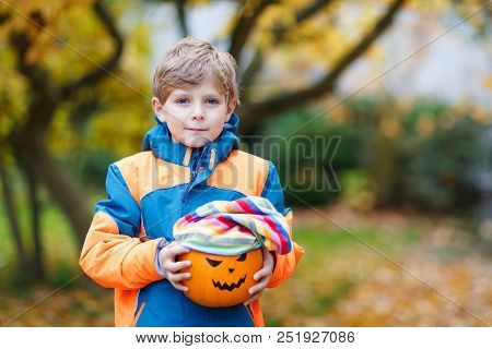 Happy Cute Little Kid Boy With Halloween Pumpkin Lantern. Funny Child In Colorful Clothes Having Fun