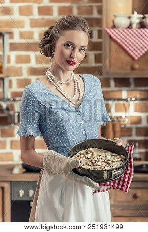 Beautiful Adult Housewife Holding Baking Trey And Looking At Camera At Kitchen