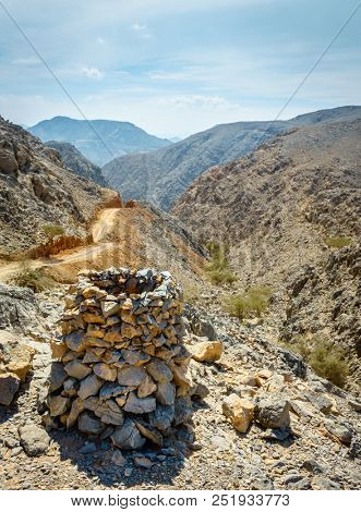 Dirt road in Al Hajar mountains in Fujairah, UAE with a rock pyramid in the foreground