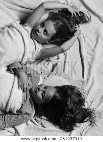 Pajama Party And Childhood Concept. Kids With Dreamy Faces And Loose Hair Lie In Bed. Schoolgirls In