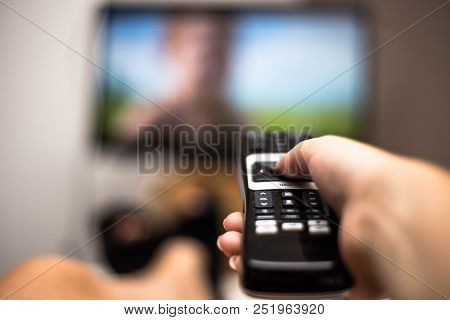 Hand Holding Use Remote Control And Watching Tv In House On A Colorful Flatscreen Modern Design