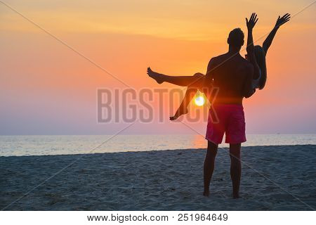 Couple Watching The Sunset On The Beach