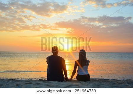Couple Watching The Sunset On The Beach