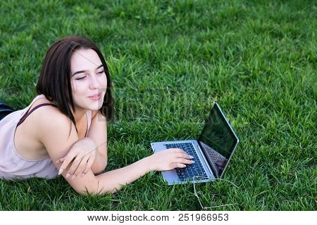 Waist-up Portrait Of Charming Young Female Working On Portative Computer And Laying On Fresh Green G
