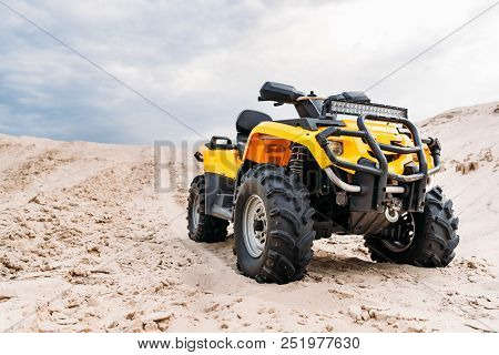 Bottom View Of Modern Yellow All-terrain Vehicle Standing In Desert On Cloudy Day