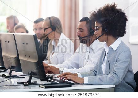 Young Customer Service Executives Using Earphones Working In Call Center