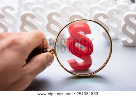 A Person Looking At Red Paragraph Symbol Through Magnifying Glass