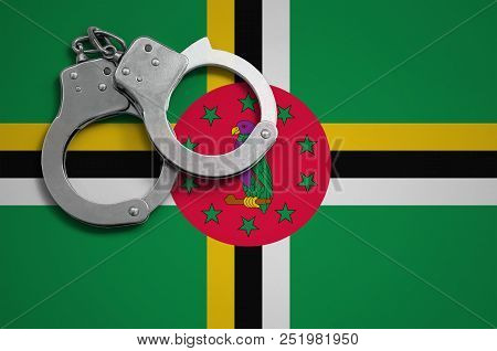 Dominica Flag  And Police Handcuffs. The Concept Of Crime And Offenses In The Country