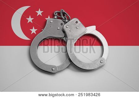 Singapore Flag  And Police Handcuffs. The Concept Of Observance Of The Law In The Country And Protec