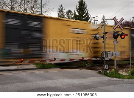 Street Level Railway Crossing.  A Train Passes A Level Train Crossing With The Crossing Arms Down An