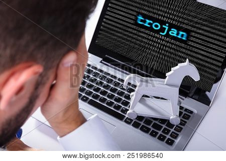 Businessman With Laptop Screen Showing Trojan Text With Binary Digits