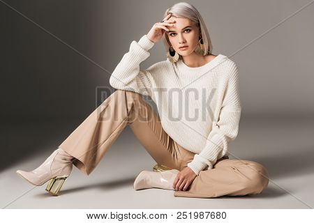 Attractive Fashionable Woman Posing In White Trendy Sweater, Beige Pants And Autumn Heels, On Grey