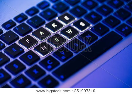 Fake News Written On A Backlit Laptop Keyboard Close-up With Selective Focus In A Blue Ambiant Light
